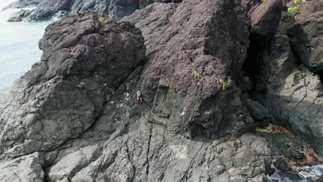 excursionista masculino haciendo senderismo en una formación rocosa masiva junto al mar en catanduanes, filipinas