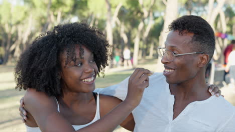 happy young black couple smiling and hugging in a park