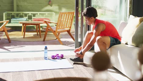 fit african american man exercising at home and tying the laces