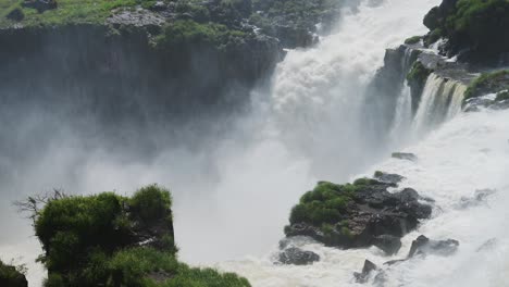 huge cliff edge with thick waterfalls pouring off steep river into splashing water abyss, flying water splash from rough aggressive slow motion waterfalls in iguazu falls, argentina, south america