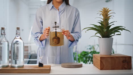 hands pouring green tea on contemporary kitchen. woman enjoy hot herbal beverage