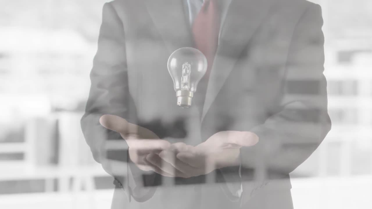 Animation of light bulb over businessman's hands in office background