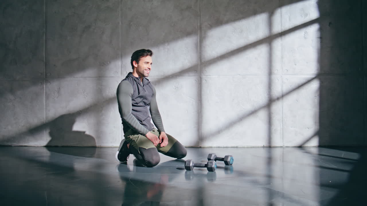 Sportive man training hard taking break after weightlifting. Guy feeling happy