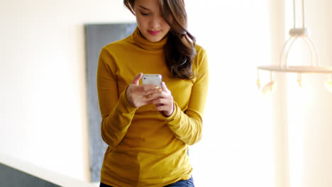 Woman-using-mobile-phone-in-living-room