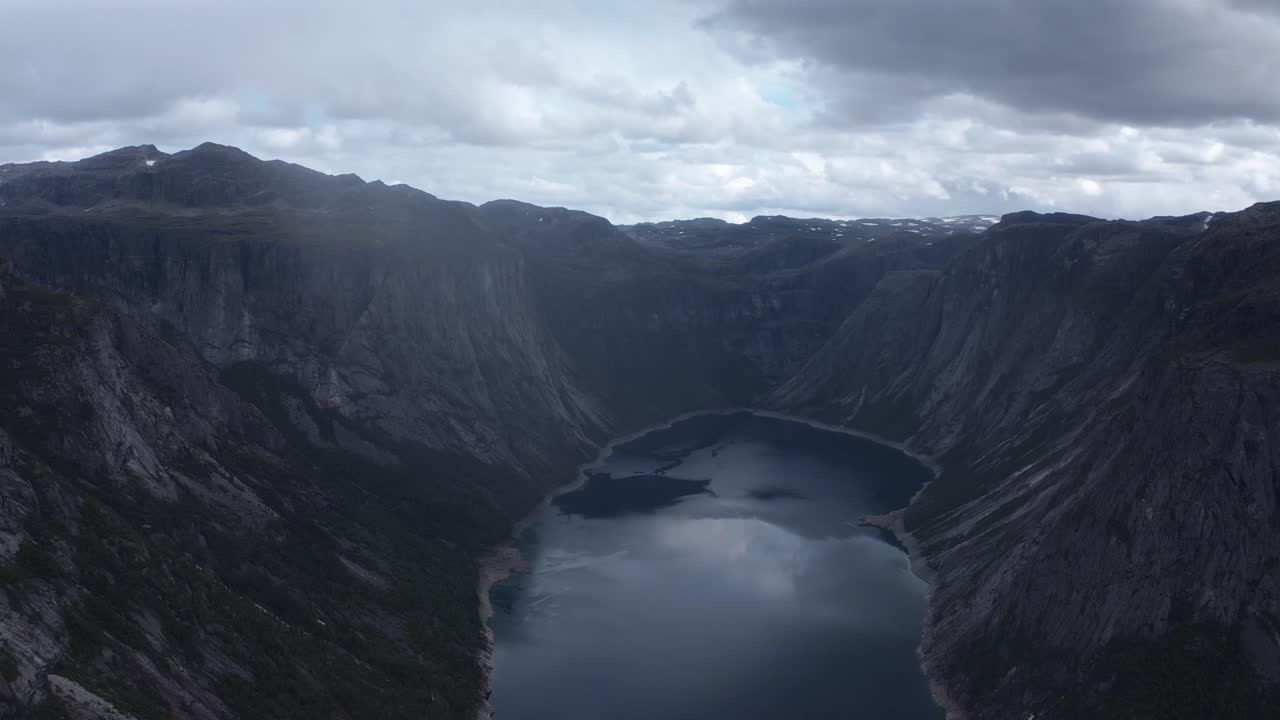 Dramatic norwegian landscape with mountains and calm water below, aerial view