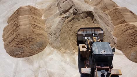 vista aérea de un tractor que mueve una carga de arena fresca en una planta de hormigón