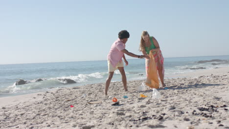joven mujer caucásica y hombre afroamericano limpian una playa, con espacio de copia
