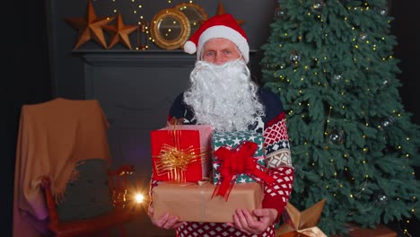 senior grandfather parodies santa claus presenting christmas gift box, holidays celebration at home