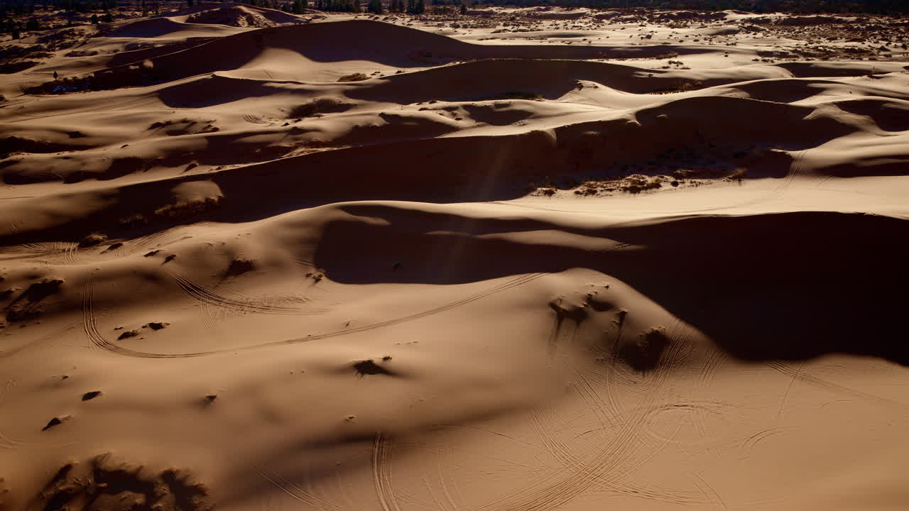 The drone looks directly down on a vibrant patchwork of pink sand dunes in southern Utah.