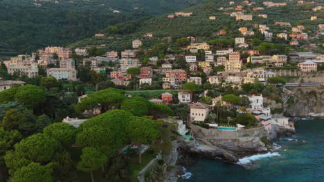drone pushes towards aerial view of colorful coastal town in italy with blue sea, rocky shores and lush green trees surround