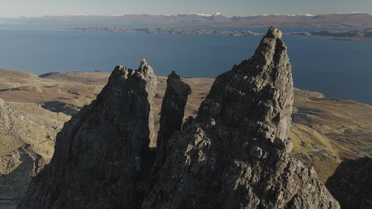 Forward dolly shot over Isle of Skye mountain peaks, leading to the blue ocean on the horizon