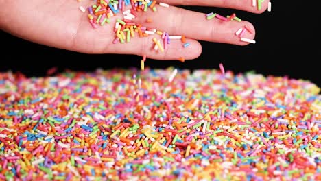 hands releasing rainbow sprinkles onto a surface