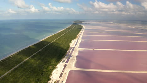 Salt-ponds-with-pink-water-along-coastal-isthmus-in-Yucatan,-Mexico