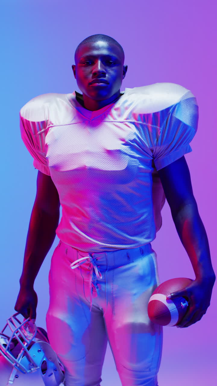 video vertical de un jugador de fútbol americano afroamericano con iluminación púrpura de neón