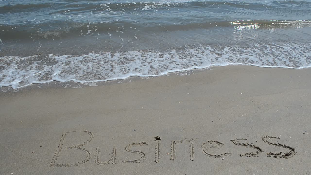 Tulisan 'business' di pasir. Syuting di pantai.