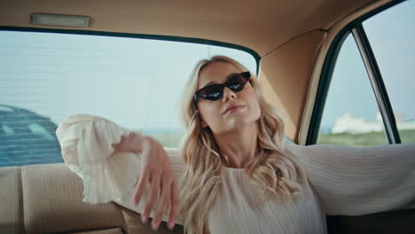 rich girl riding backseat retro automobile in sunglasses closeup. car travel