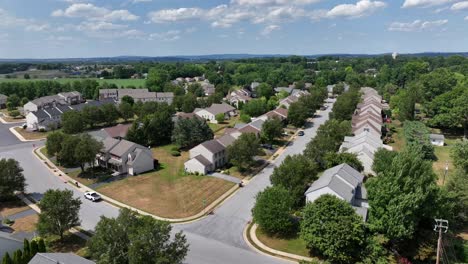 aerial approaching shot of american residential area with one family homes with green trees