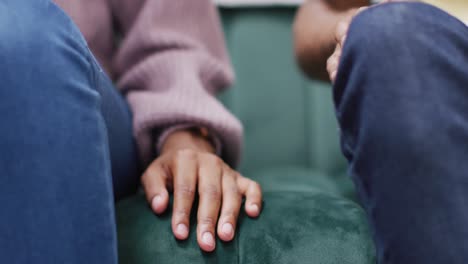 manos de una pareja afroamericana sentada en el sofá y tocándose