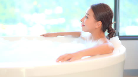 close-up of a beautiful, young, healthy woman relaxes in a luxurious spa-like bathtub full of soothing bubbles