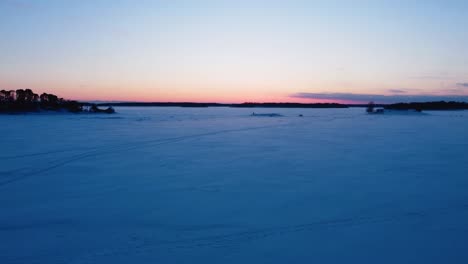 Aerial-view-risiing-over-snowy-sea-ice,-vibrant-winter-dusk-on-the-gulf-of-Finland