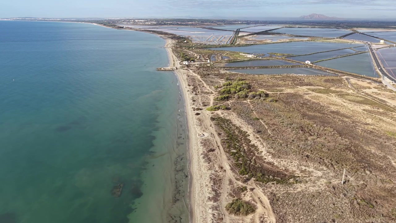 Tomada de aproximação com drone onde as salinas cor-de-rosa encontram o Mar Mediterrâneo em Santa Pola, Espanha. Vista aérea de zonas úmidas costeiras, salinas, linha costeira, contraste de água e paisagem natural cênica