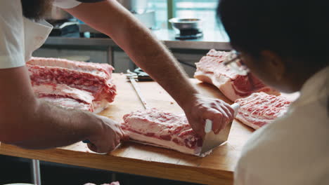 carnicero mostrando a un colega cómo pelar un corte de carne
