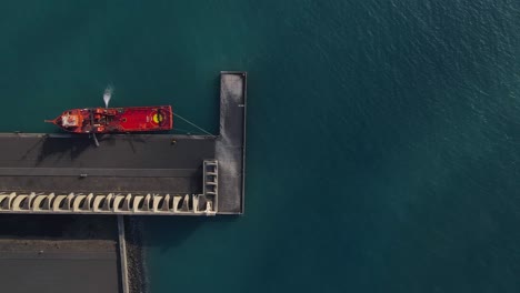 red cargo ship anchored at quay of tazacorte harbor in la palma island