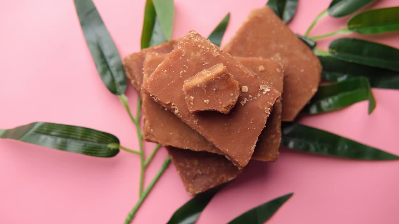 분홍색 배경에 열대 잎을 가진 갈색 설탕 큐브