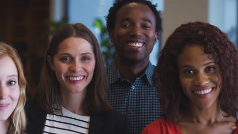 portrait of multi-cultural business team standing in modern open plan office together