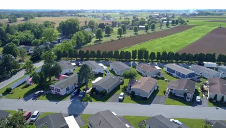 an aerial view of a well kept mobile, manufactured, prefab home park of single wide and double wide houses on a sunny day