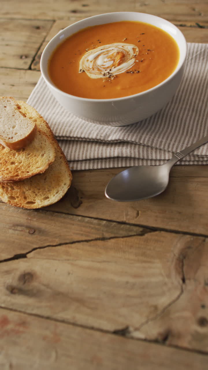 video vertical de sopa de verduras de crema y pan acostado en una superficie de madera