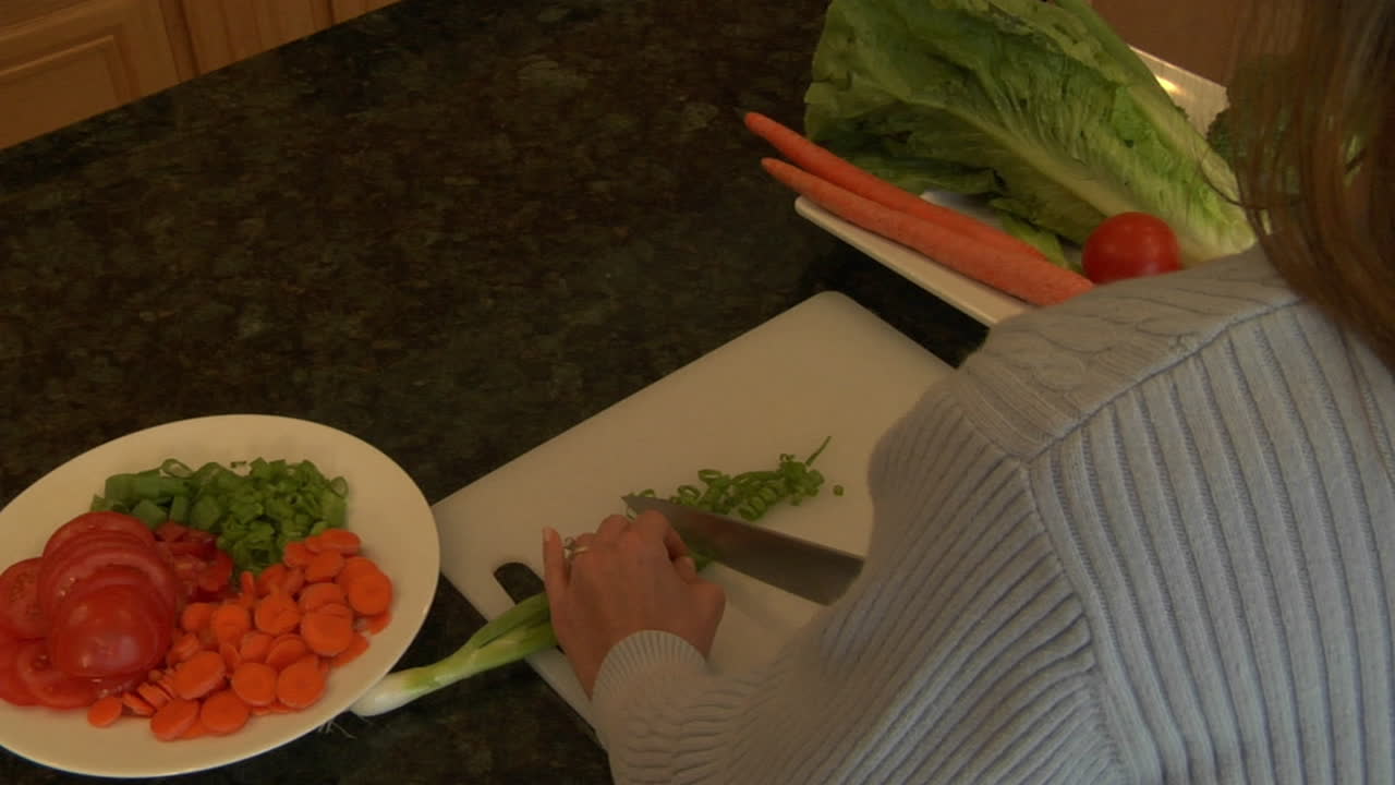 여자가 도마 위에서 파를 썰고 있다