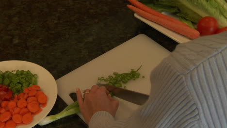 a woman chops green onions on a cutting board