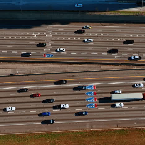 cars moving quickly by the wide-lane road to both sides. drone footage above the highway with heavy traffic at daytime.