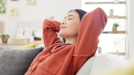 Asian-woman,-happy-or-relax-on-sofa-in-house