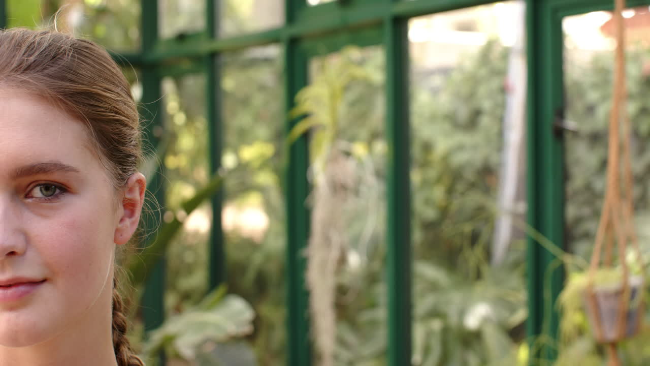 Smiling woman in glass house with green plants, enjoying peaceful environment, copy space