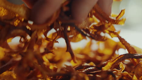 close up shot of a man's hand picking up yellow aromatic dried spice herbs from a table