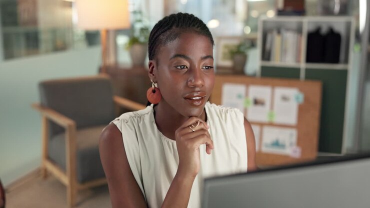 Young Black Woman Working and Thinking at Computer in Office