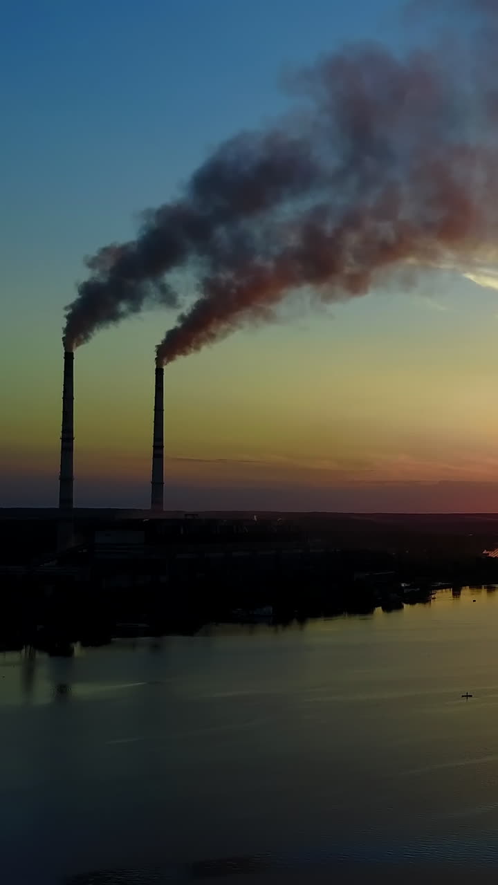 Smoke From The Pipe Factory Near The River. Landscape of an industrial estate with pipe factory smoke near river Vertical video