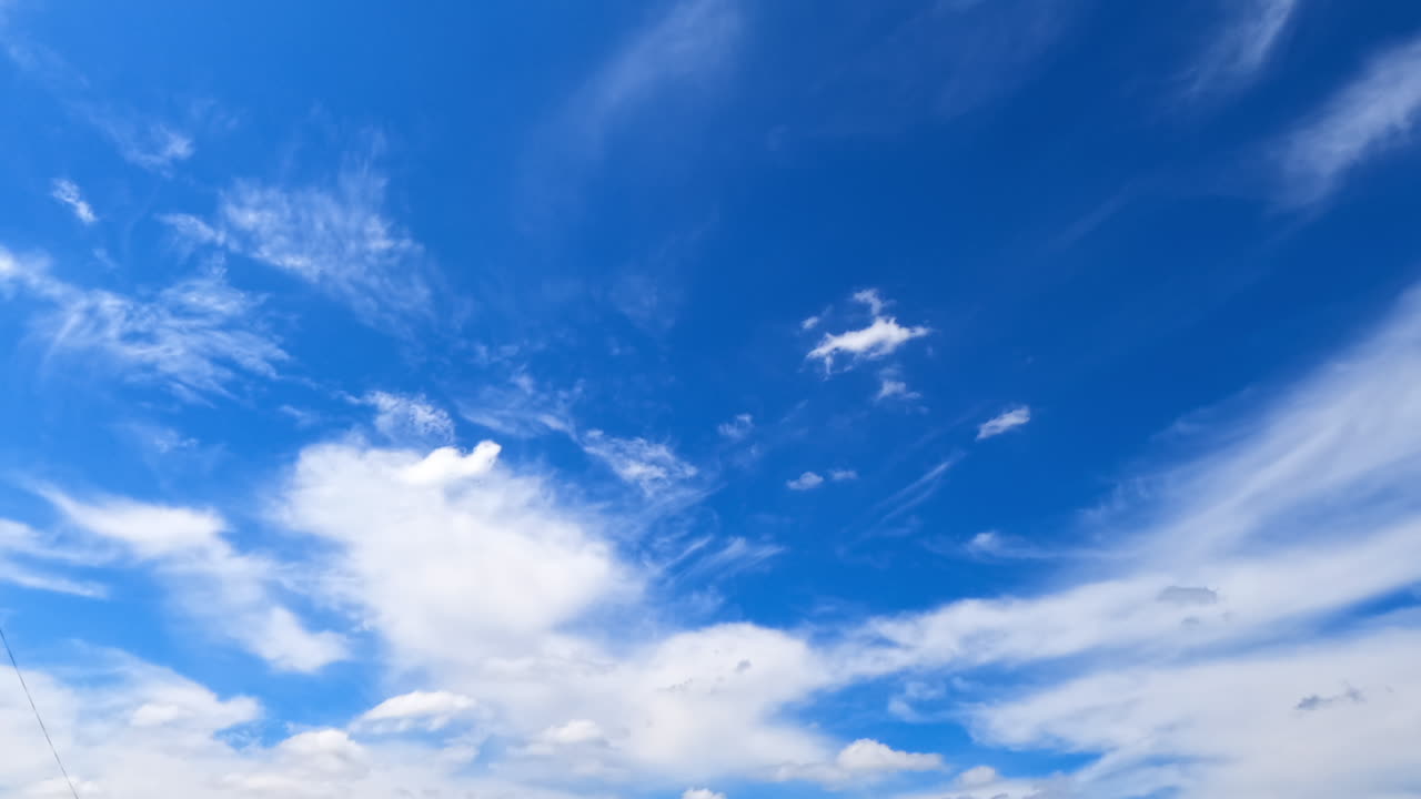 Azure sky with white stratus clouds floating by. Low angle view on the beautiful summer sky. Timelapse.