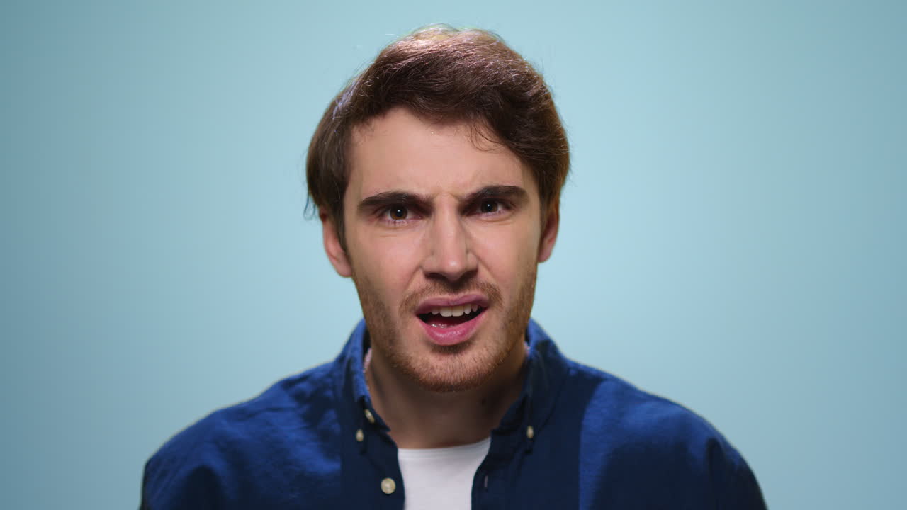 hombre disgustado gesticulando sobre un fondo azul. tipo molesto posando en el estudio