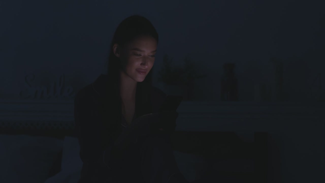 Woman using smartphone in bed at night