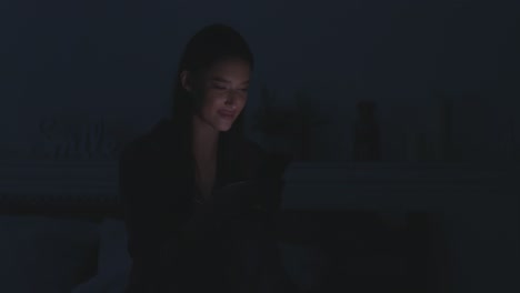 mujer usando teléfono inteligente en la cama por la noche