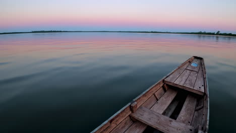 wooden boat on calm lake at sunrise/sunset