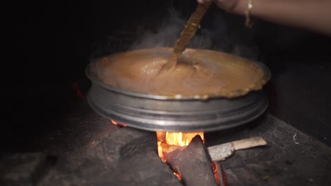 indian traditional jackfruit dessert stirred in firewood stove | wide shot | push in | slow-motion