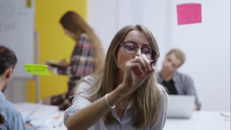 Mujer-Líder-En-Capacitación-Corporativa-Usando-Una-Pared-De-Vidrio-Para-Escribir-Estrategia