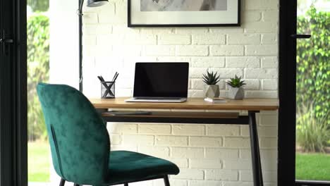 a modern workspace setup: stylish desk with laptop, green chair, decorative plants, and bright natural light for a productive environment