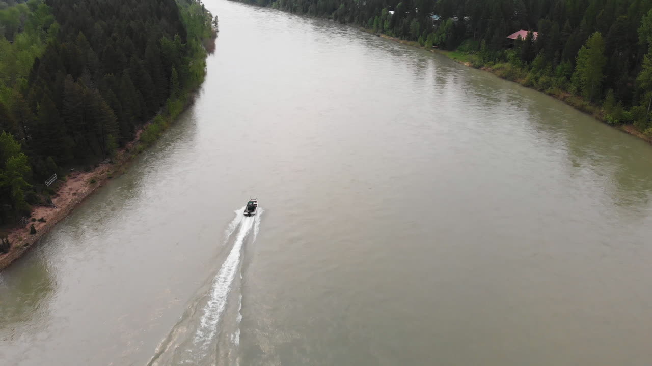 съемка с воздуха за лодкой, несущейся вверх по течению на средней развилке реки флэтхед, монтана