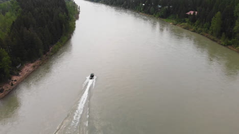 aerial shot following a boat speeding upstream on the middle fork flathead river, montana