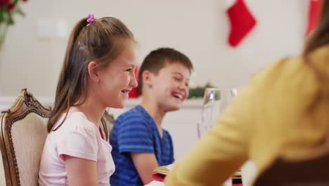 Caucasian-boy-and-girl-smiling-while-sitting-on-dining-table